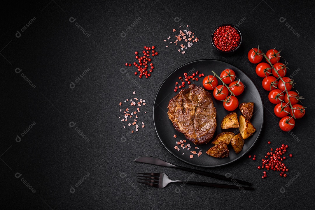 Delicioso bife com sal, especiarias e ervas em uma placa cerâmica sobre um fundo escuro de concreto