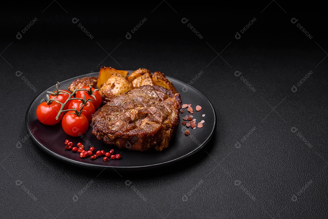 Delicioso bife com sal, especiarias e ervas em uma placa cerâmica sobre um fundo escuro de concreto