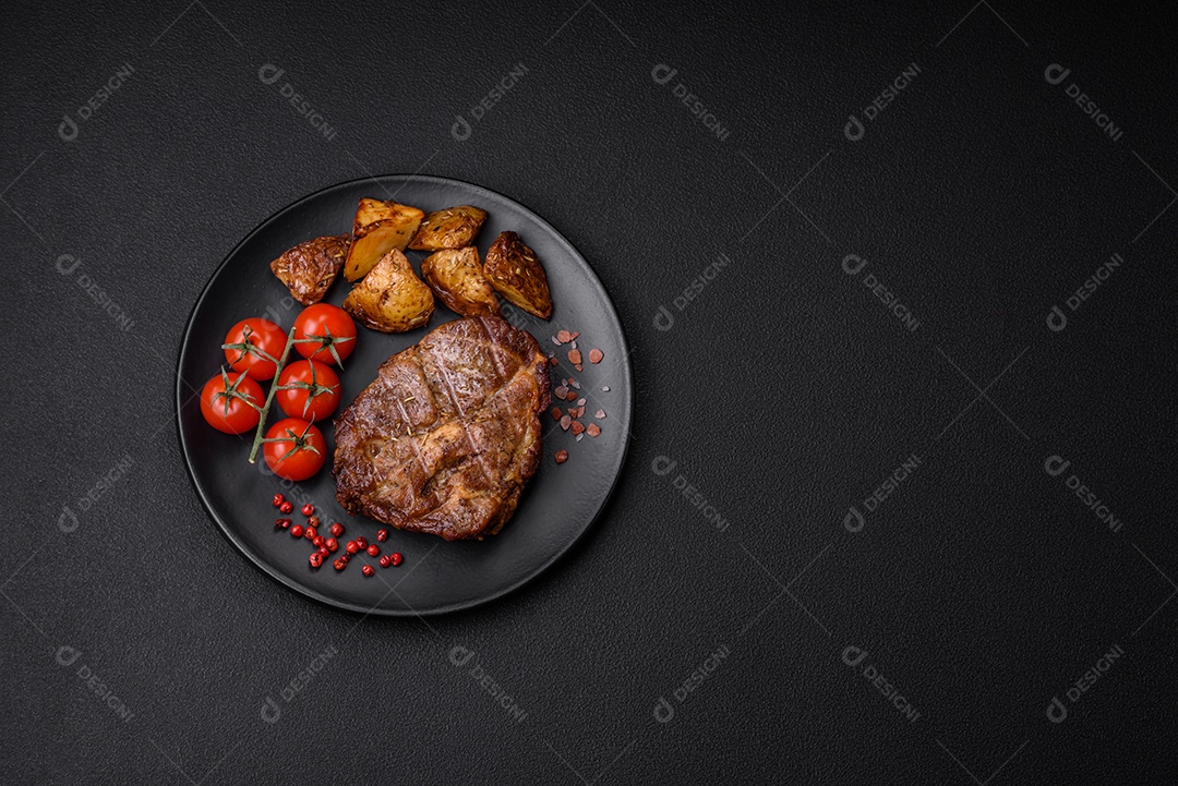 Delicioso bife com sal, especiarias e ervas em uma placa cerâmica sobre um fundo escuro de concreto