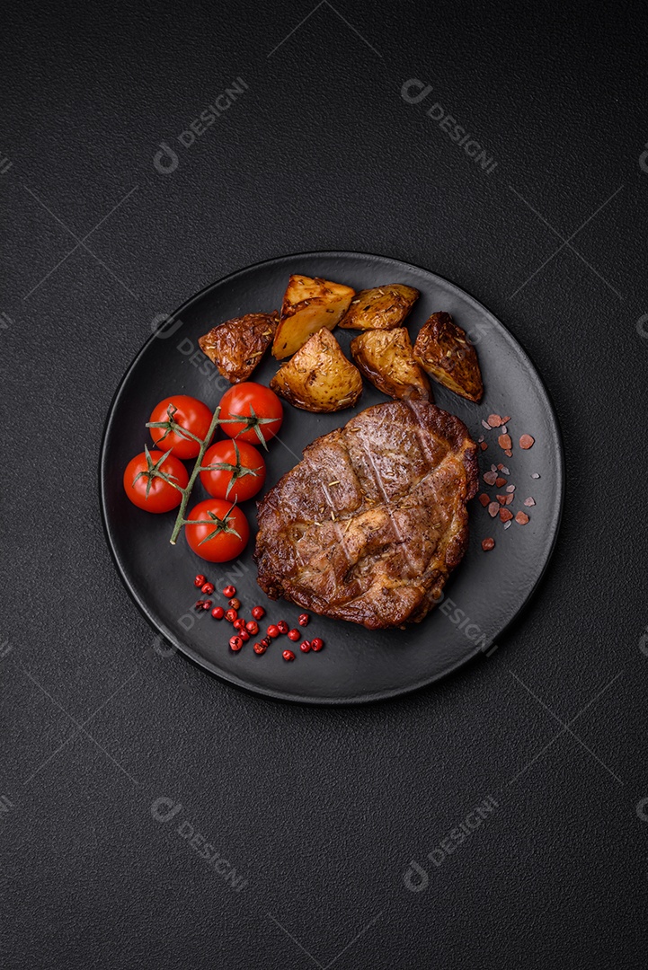 Delicioso bife com sal, especiarias e ervas em uma placa cerâmica sobre um fundo escuro de concreto