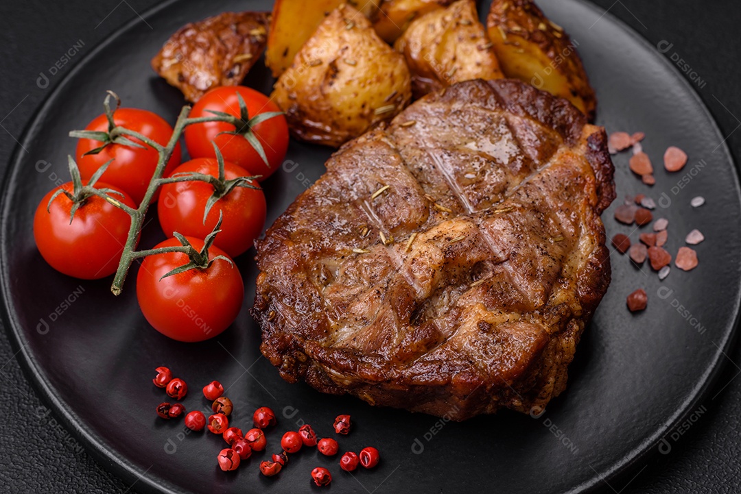 Delicioso bife com sal, especiarias e ervas em uma placa cerâmica sobre um fundo escuro de concreto