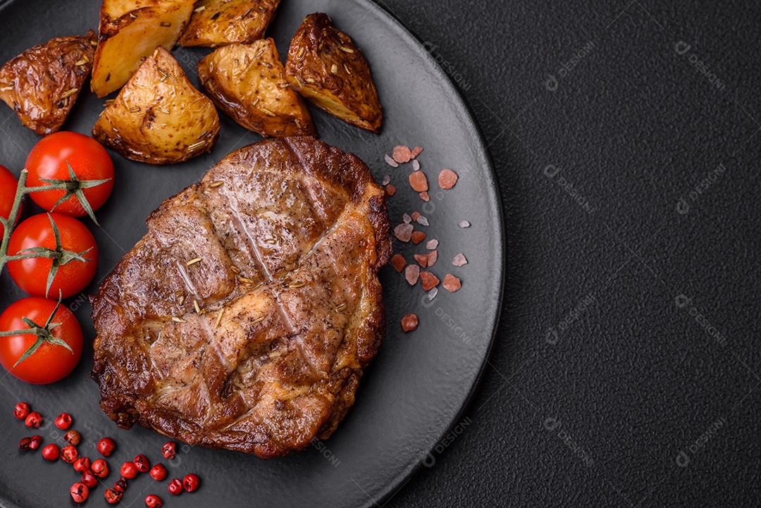 Delicioso bife com sal, especiarias e ervas em uma placa cerâmica sobre um fundo escuro de concreto