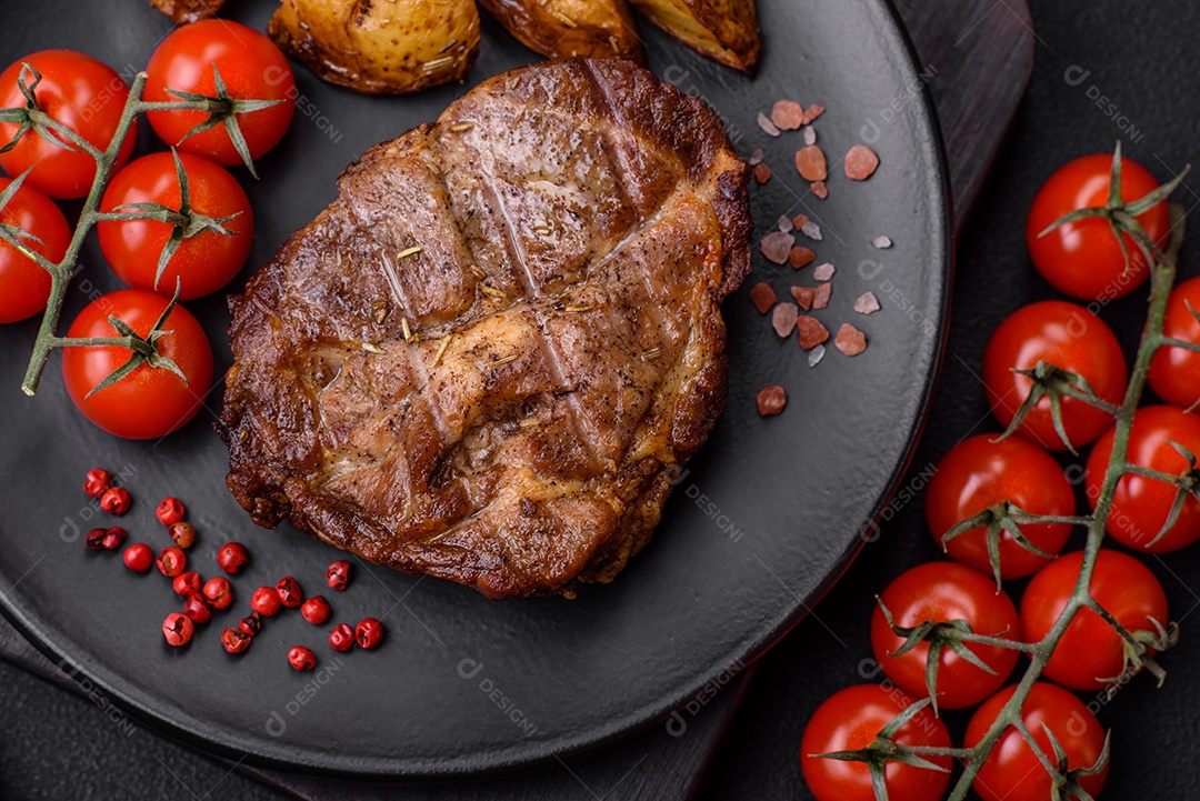 Delicioso bife com sal, especiarias e ervas em uma placa cerâmica sobre um fundo escuro de concreto