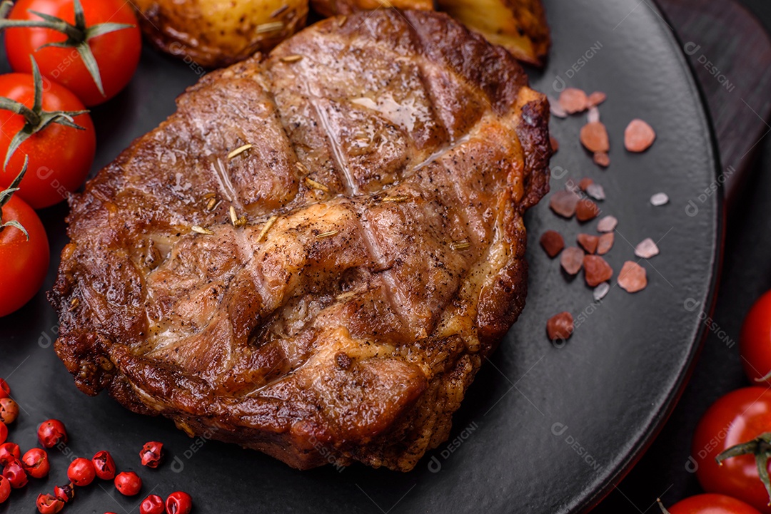 Delicioso bife com sal, especiarias e ervas em uma placa cerâmica sobre um fundo escuro de concreto