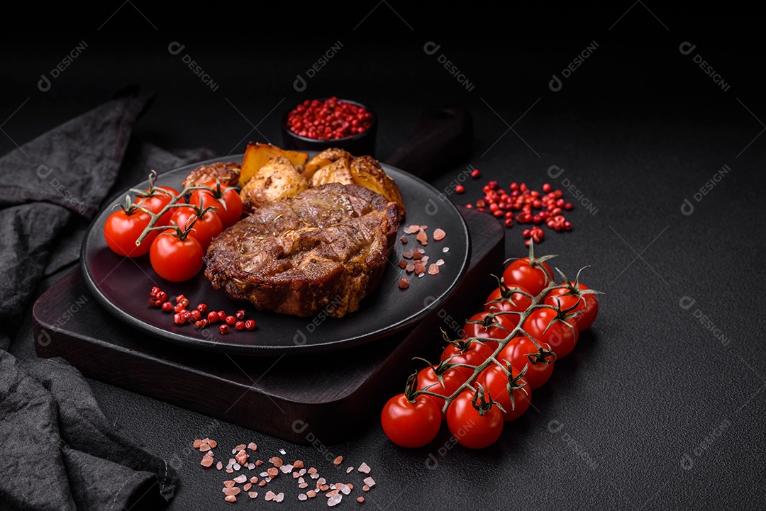 Delicioso bife com sal, especiarias e ervas em uma placa cerâmica sobre um fundo escuro de concreto