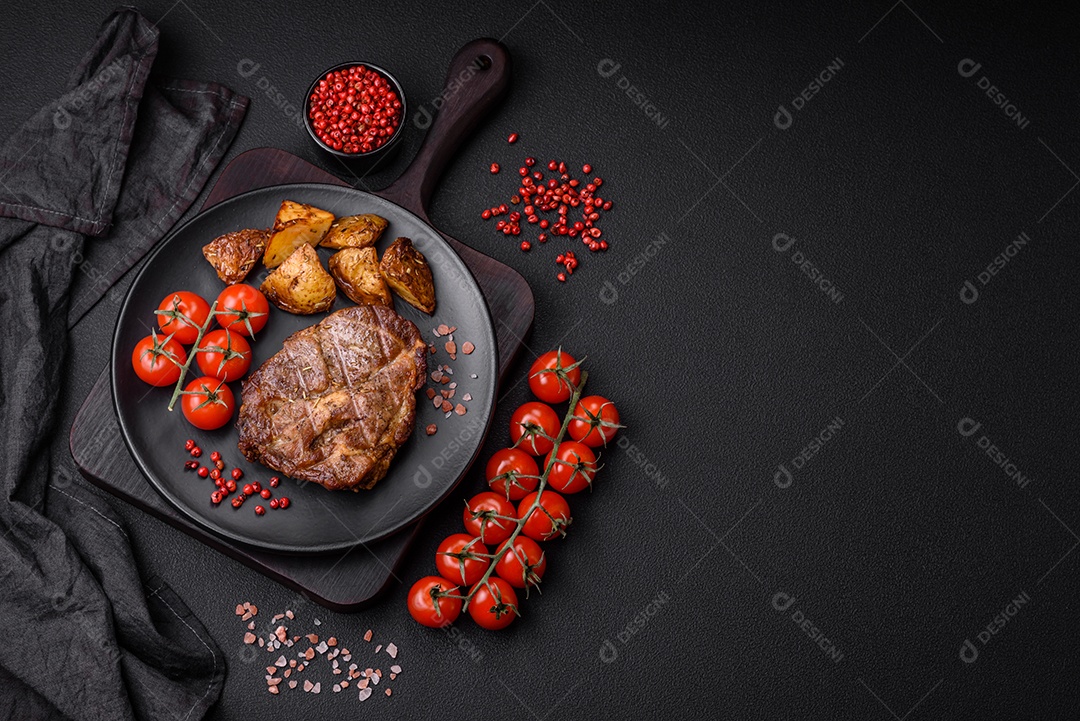 Delicioso bife com sal, especiarias e ervas em uma placa cerâmica sobre um fundo escuro de concreto