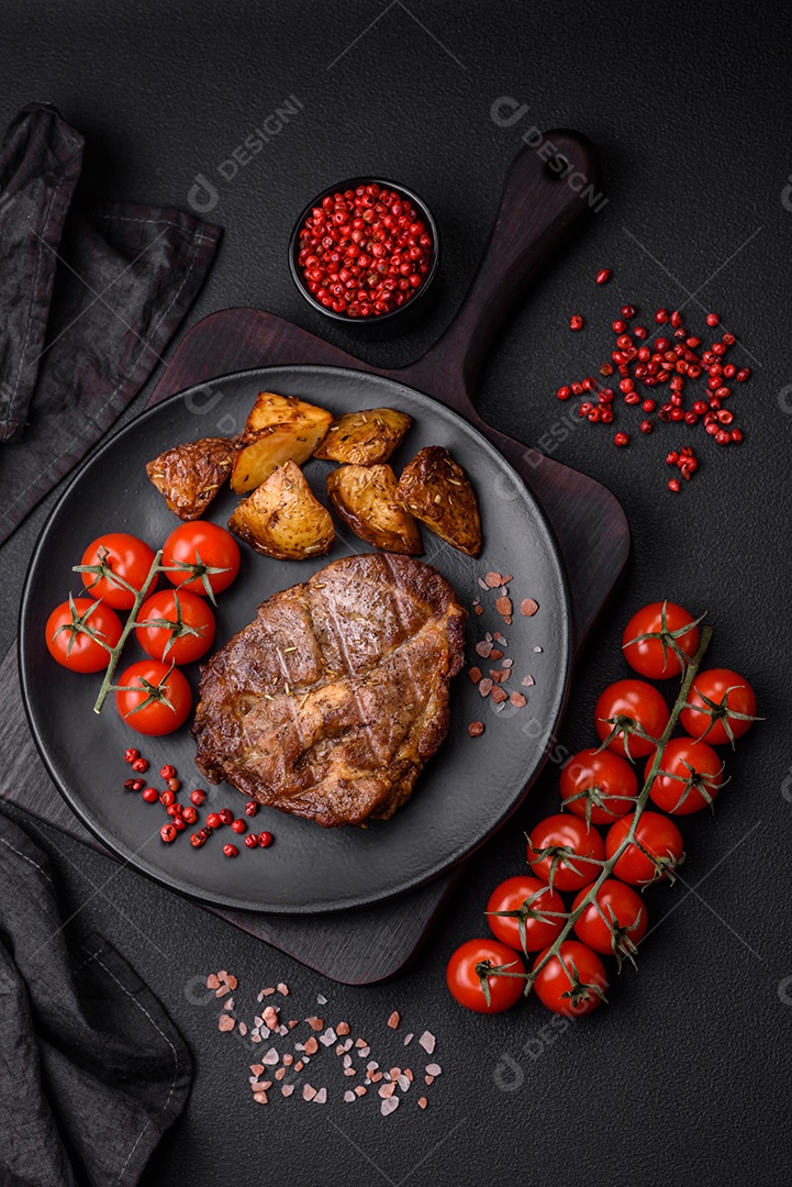 Delicioso bife com sal, especiarias e ervas em uma placa cerâmica sobre um fundo escuro de concreto