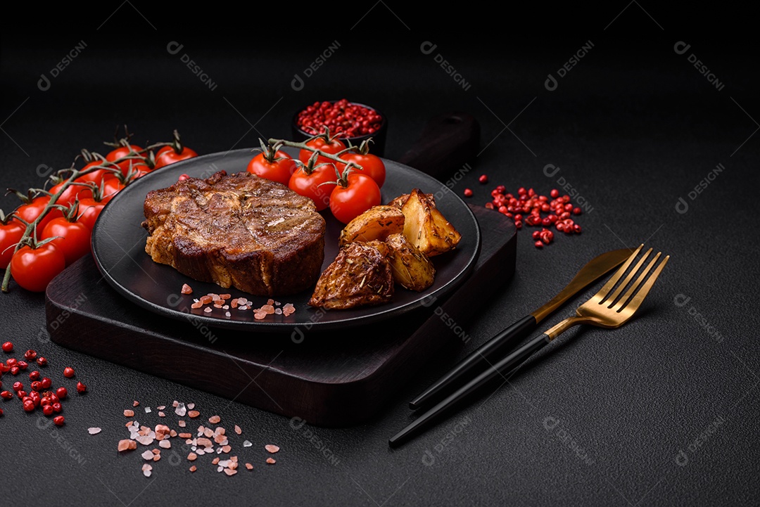 Delicioso bife com sal, especiarias e ervas em uma placa cerâmica sobre um fundo escuro de concreto