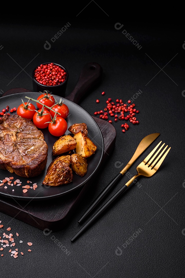 Delicioso bife com sal, especiarias e ervas em uma placa cerâmica sobre um fundo escuro de concreto