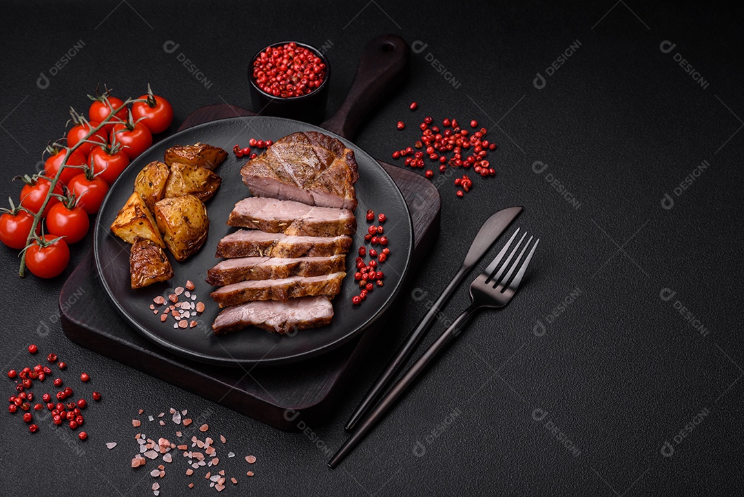 Delicioso bife com sal, especiarias e ervas em uma placa cerâmica sobre um fundo escuro de concreto