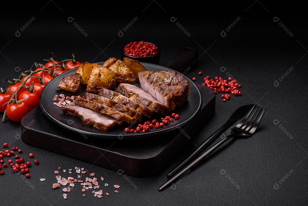 Delicioso bife com sal, especiarias e ervas em uma placa cerâmica sobre um fundo escuro de concreto