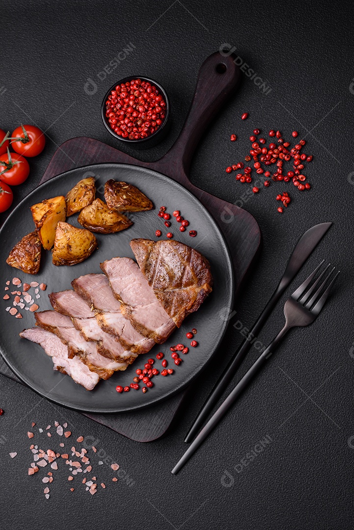 Delicioso bife com sal, especiarias e ervas em uma placa cerâmica sobre um fundo escuro de concreto
