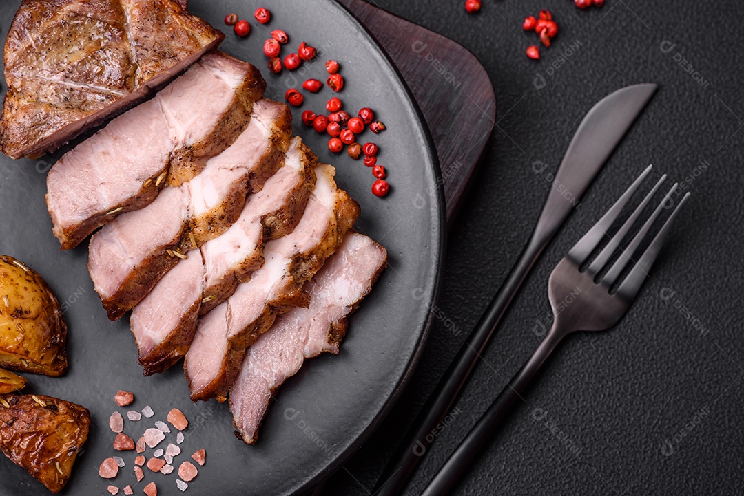 Delicioso bife com sal, especiarias e ervas em uma placa cerâmica sobre um fundo escuro de concreto