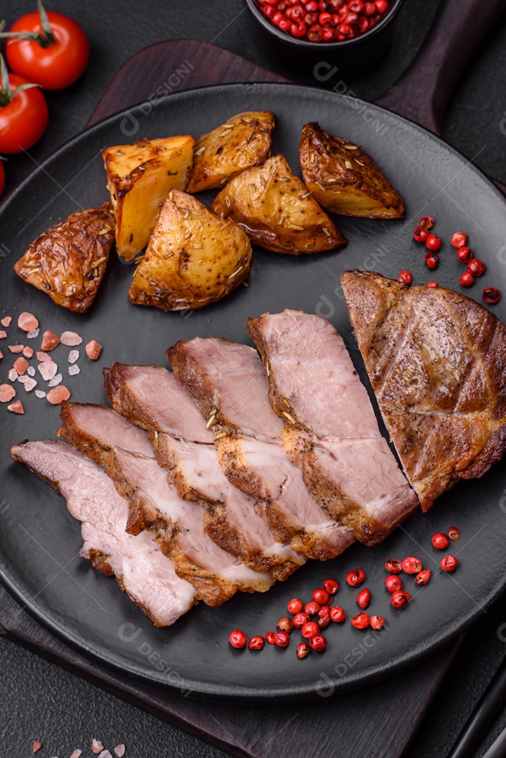 Delicioso bife com sal, especiarias e ervas em uma placa cerâmica sobre um fundo escuro de concreto