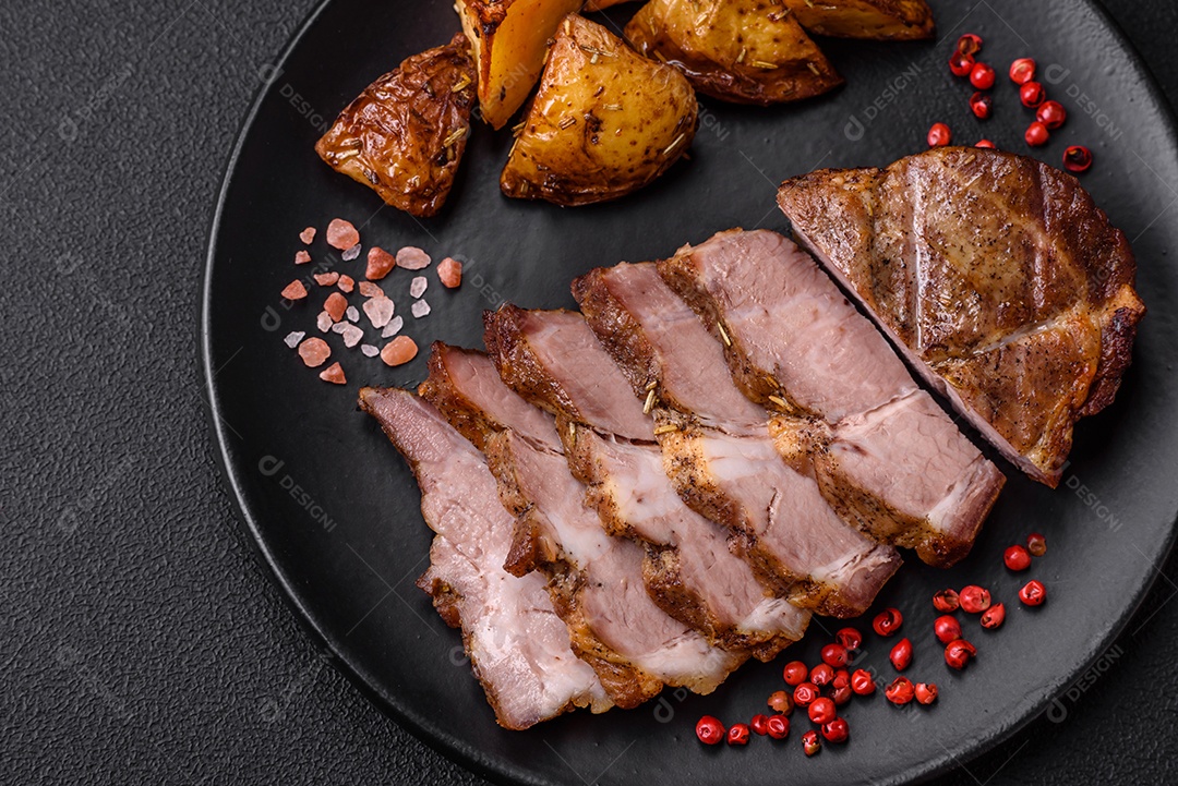 Delicioso bife com sal, especiarias e ervas em uma placa cerâmica sobre um fundo escuro de concreto