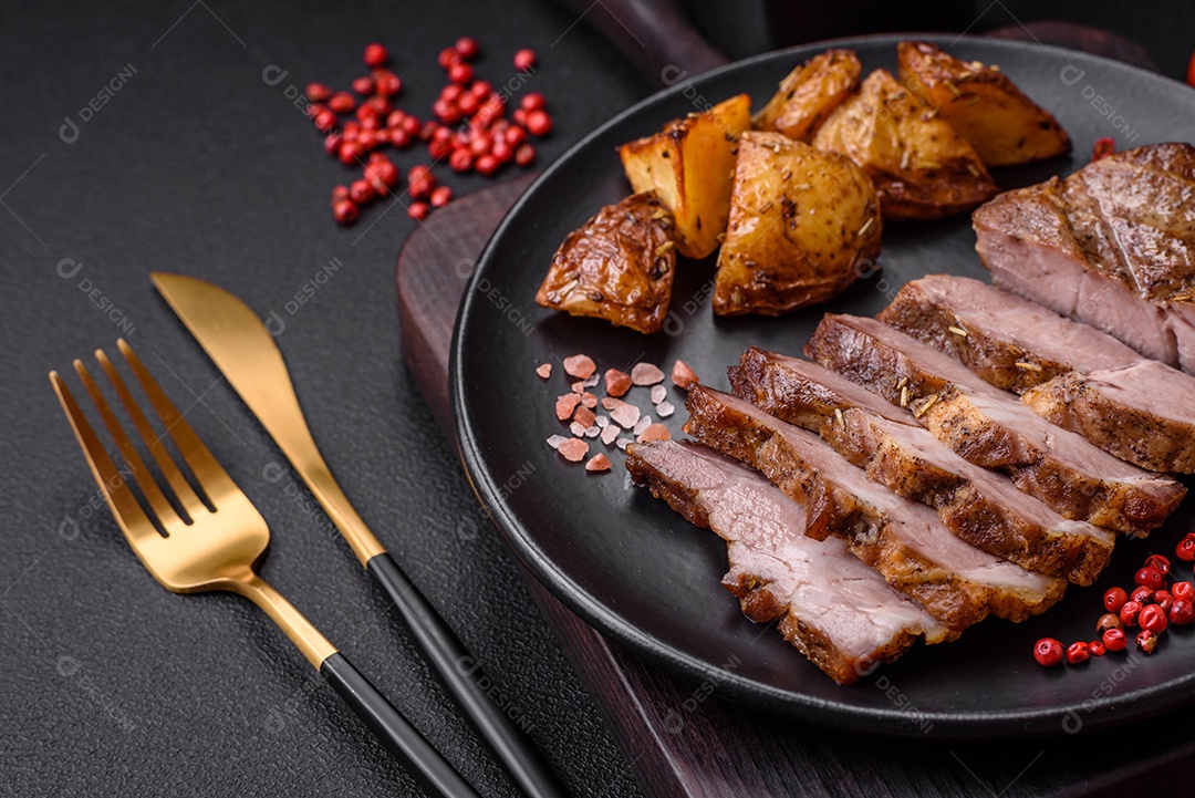 Delicioso bife suculento de porco ou bife grelhado com sal, especiarias e ervas sobre um fundo de concreto texturizado