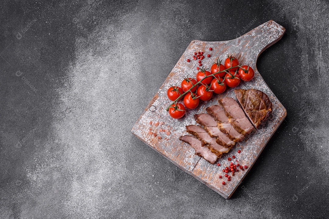 Delicioso bife com sal, especiarias e ervas em uma placa cerâmica sobre um fundo escuro de concreto