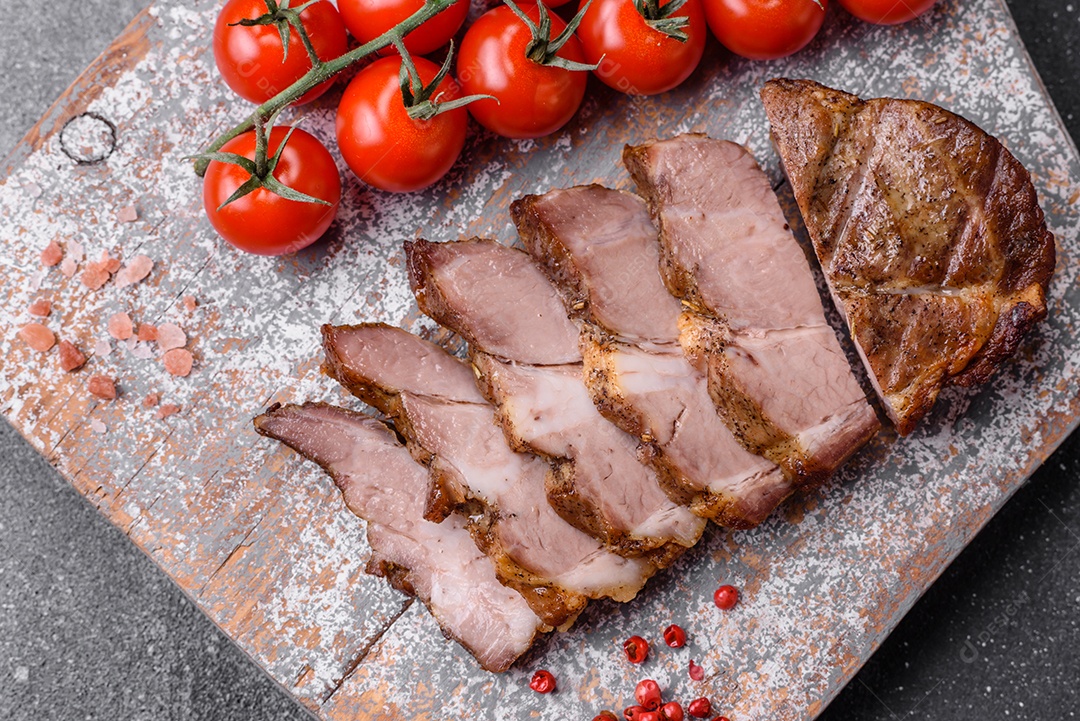 Delicioso bife com sal, especiarias e ervas em uma placa cerâmica sobre um fundo escuro de concreto
