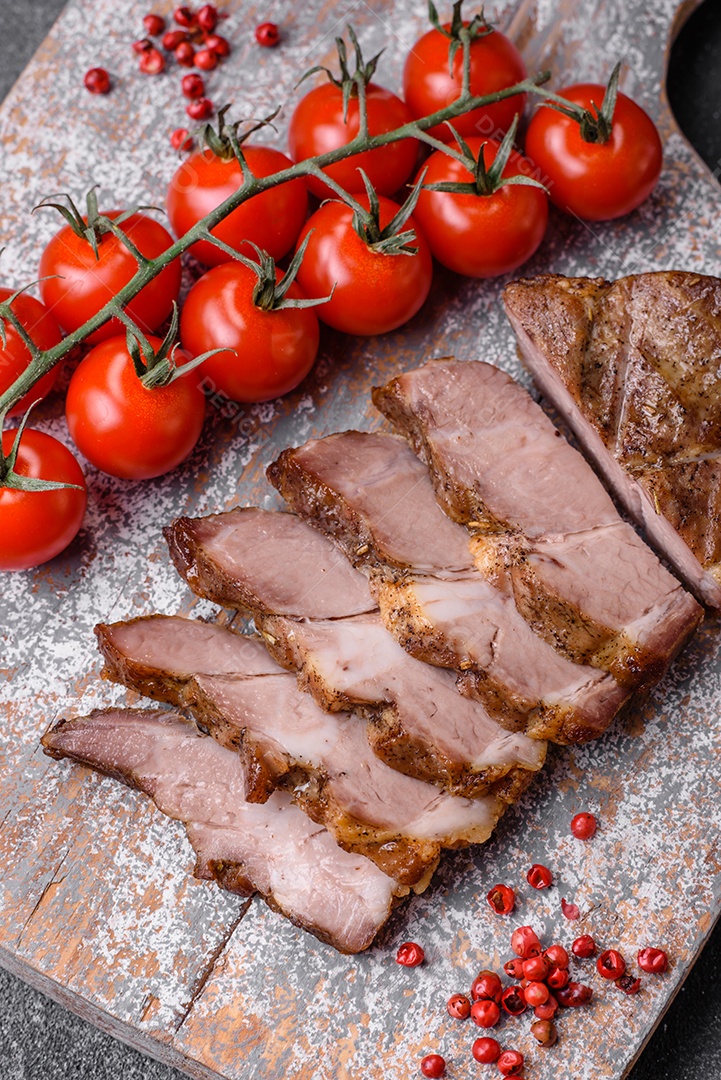 Delicioso bife com sal, especiarias e ervas em uma placa cerâmica sobre um fundo escuro de concreto