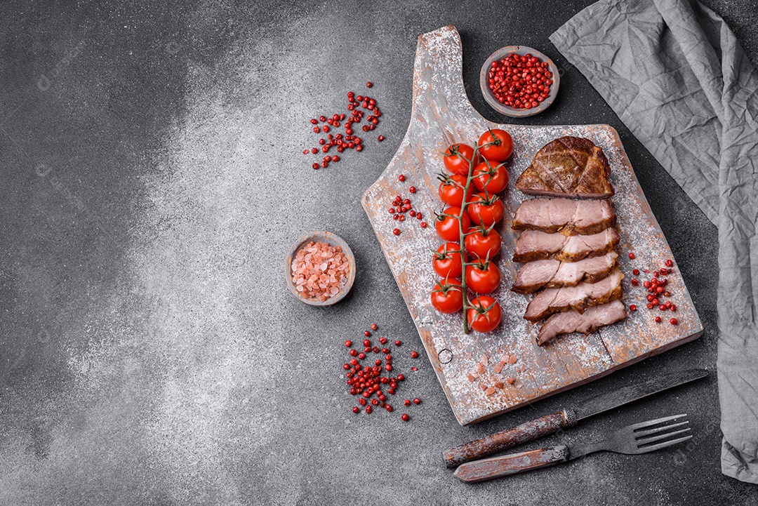 Delicioso bife com sal, especiarias e ervas em uma placa cerâmica sobre um fundo escuro de concreto