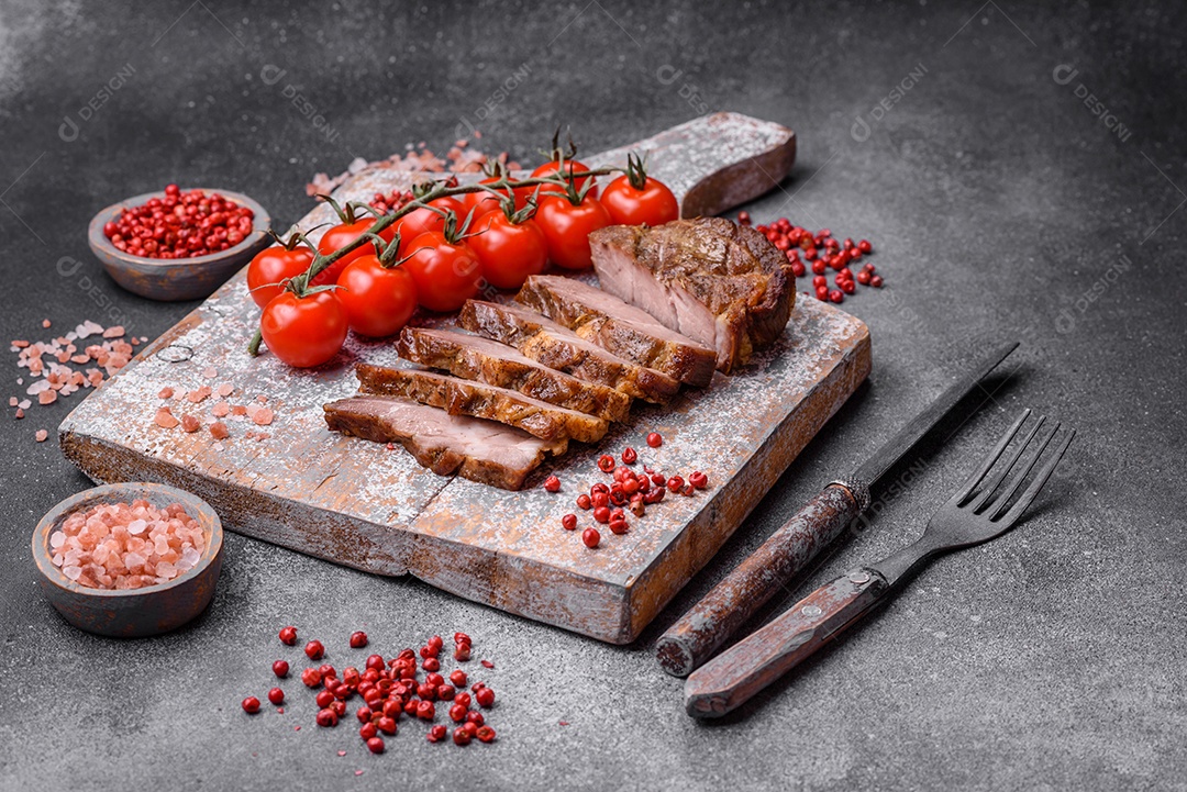 Delicioso bife com sal, especiarias e ervas em uma placa cerâmica sobre um fundo escuro de concreto