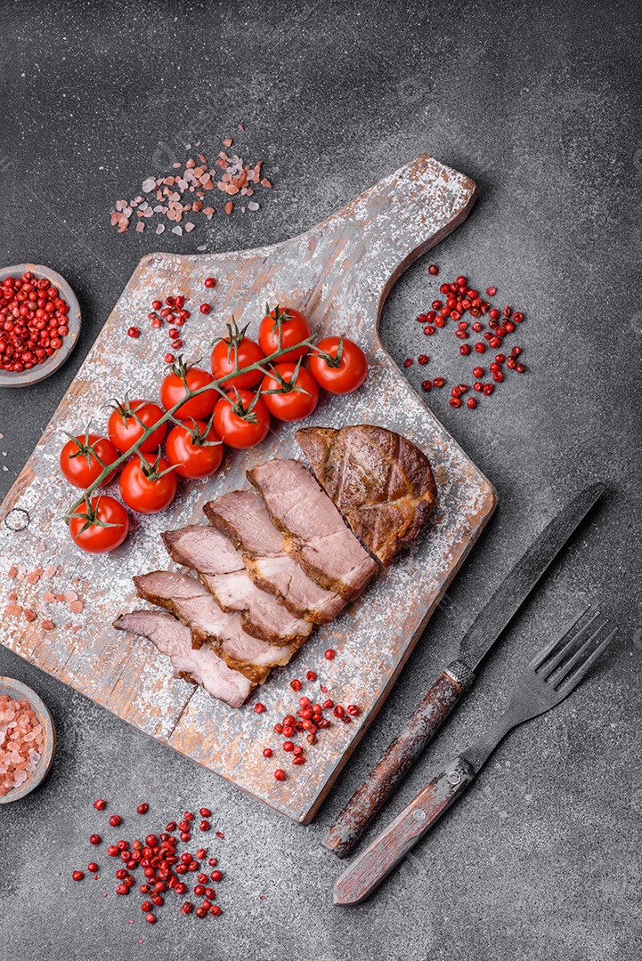 Delicioso bife com sal, especiarias e ervas em uma placa cerâmica sobre um fundo escuro de concreto