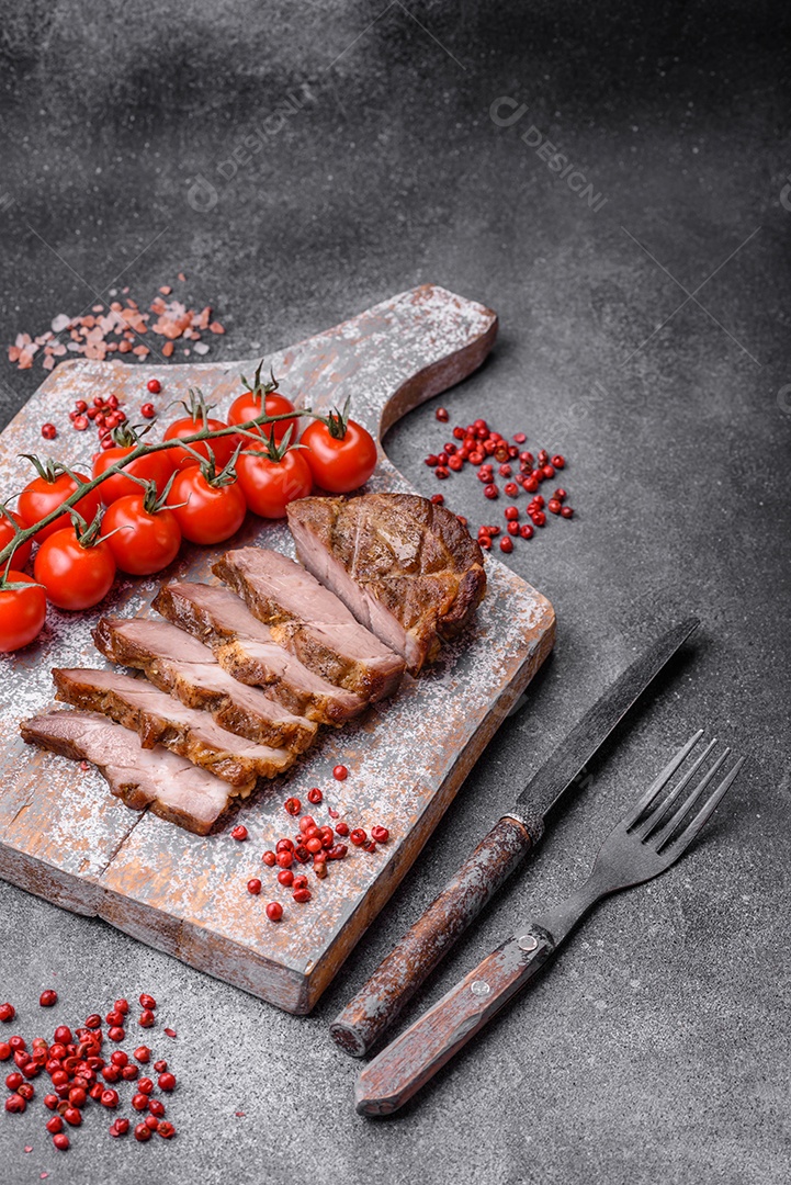 Delicioso bife com sal, especiarias e ervas em uma placa cerâmica sobre um fundo escuro de concreto