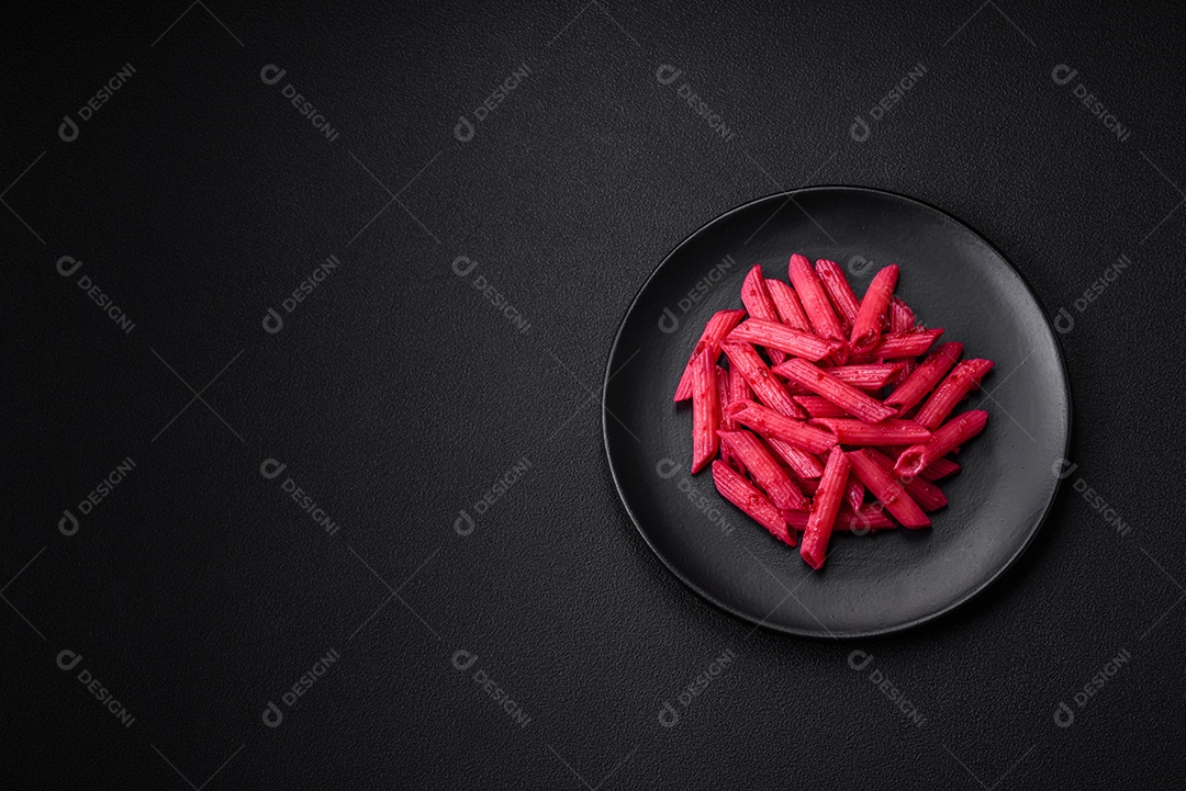 Deliciosa massa penne com beterraba, queijo, sal e especiarias sobre um fundo escuro de concreto