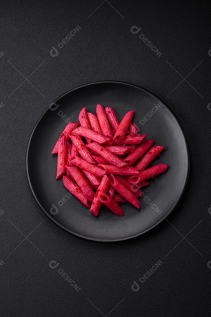 Deliciosa massa penne com beterraba, queijo, sal e especiarias sobre um fundo escuro de concreto