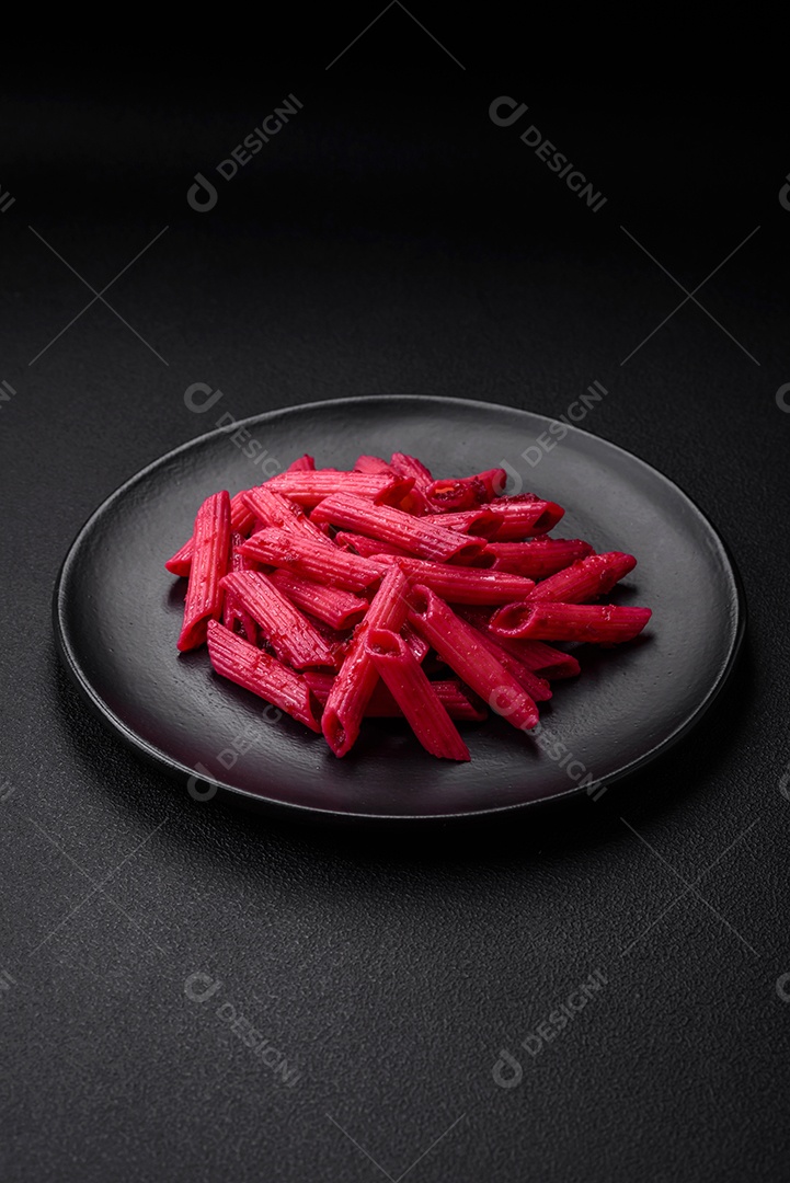 Deliciosa massa penne com beterraba, queijo, sal e especiarias sobre um fundo escuro de concreto