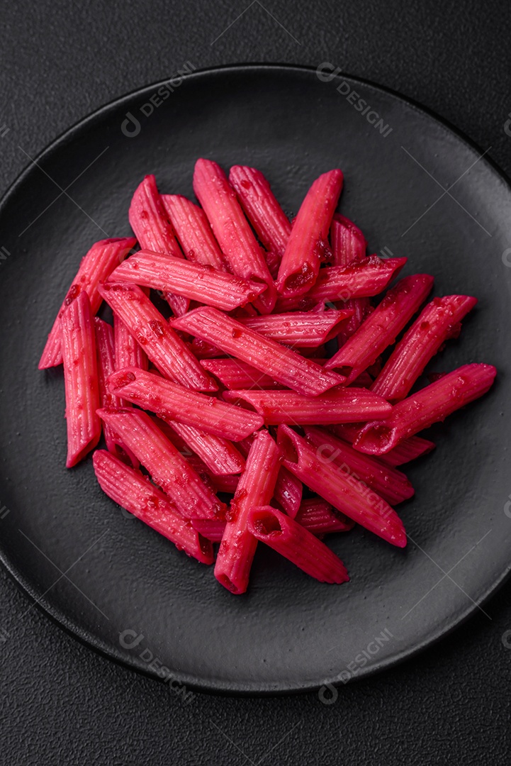 Deliciosa massa penne com beterraba, queijo, sal e especiarias sobre um fundo escuro de concreto