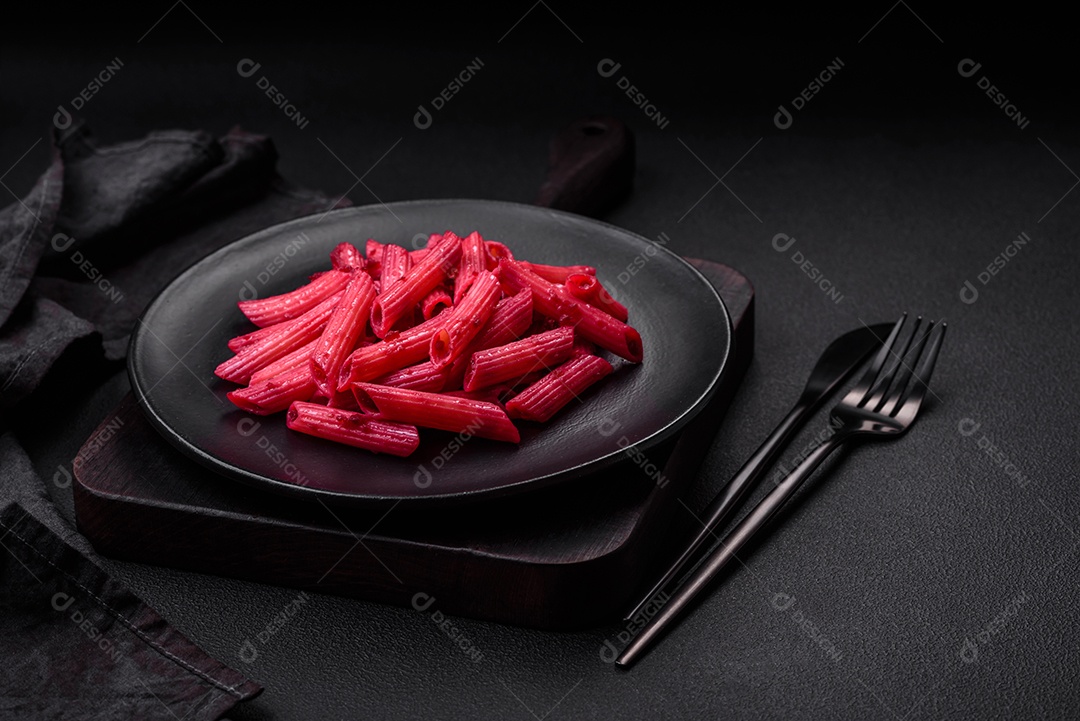 Deliciosa massa penne com beterraba, queijo, sal e especiarias sobre um fundo escuro de concreto