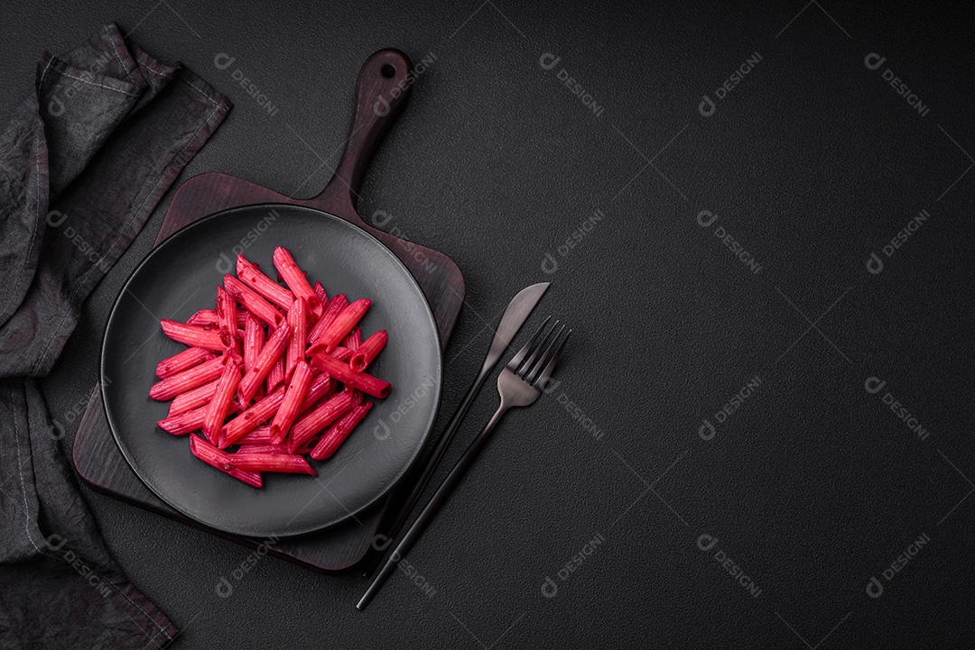 Deliciosa massa penne com beterraba, queijo, sal e especiarias sobre um fundo escuro de concreto