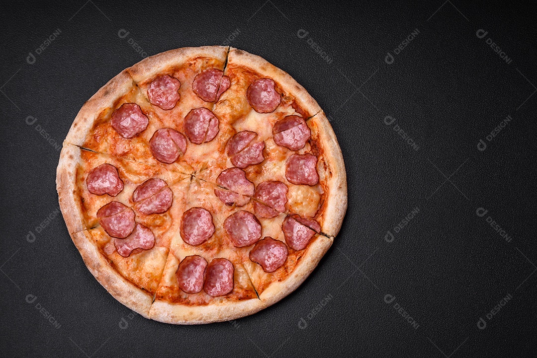 Saborosa pizza fresca com salame, queijo, tomate, especiarias e sal sobre um fundo escuro de concreto