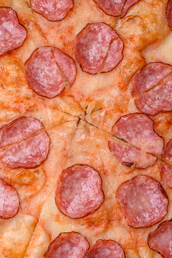 Pizza bávara com enchidos, tomates, queijo, sal e especiarias sobre um fundo escuro de concreto