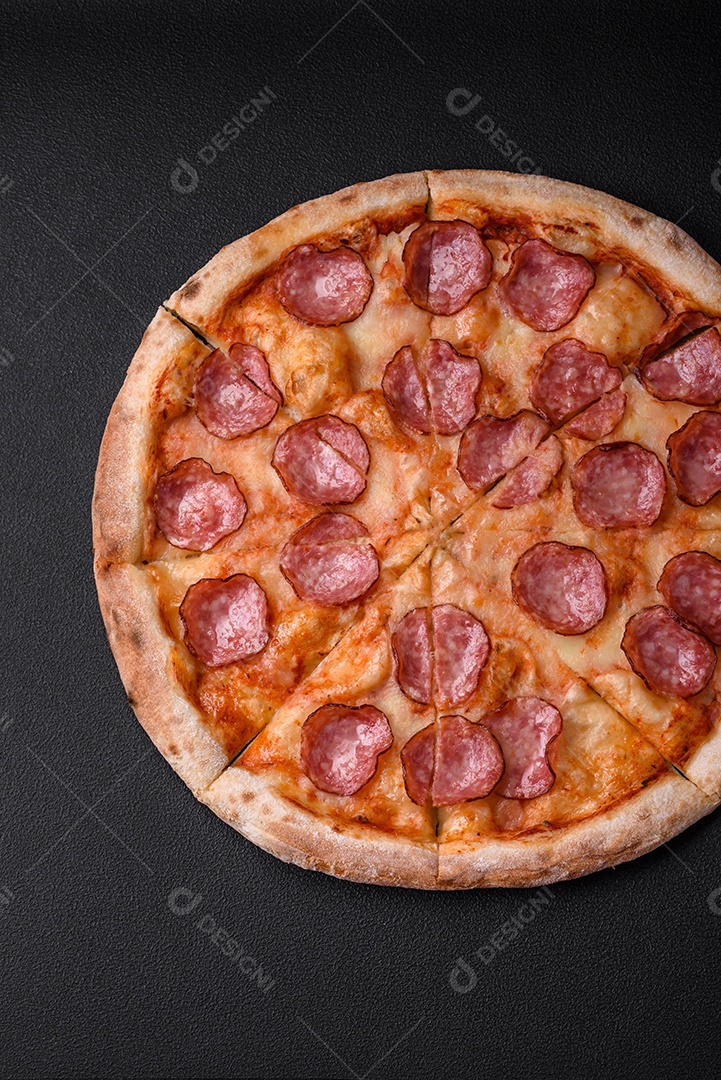 Saborosa pizza fresca com salame, queijo, tomate, especiarias e sal sobre um fundo escuro de concreto