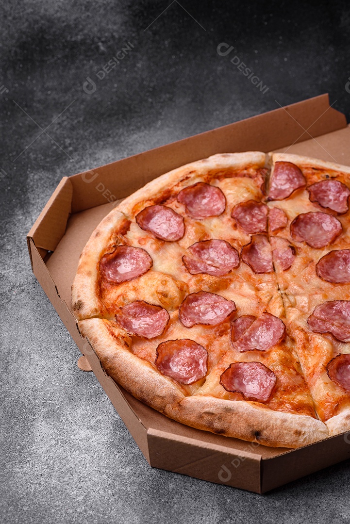 Saborosa pizza fresca com salame, queijo, tomate, especiarias e sal sobre um fundo escuro de concreto