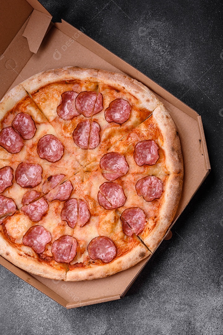 Saborosa pizza fresca com salame, queijo, tomate, especiarias e sal sobre um fundo escuro de concreto