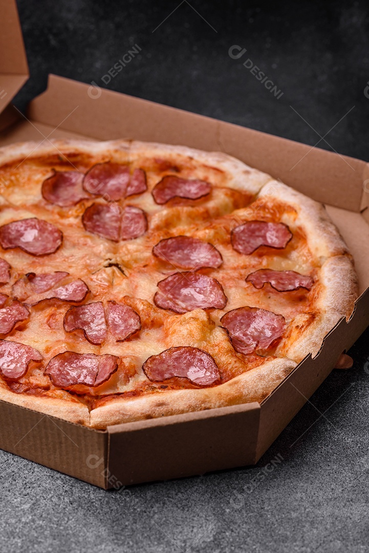 Saborosa pizza fresca com salame, queijo, tomate, especiarias e sal sobre um fundo escuro de concreto