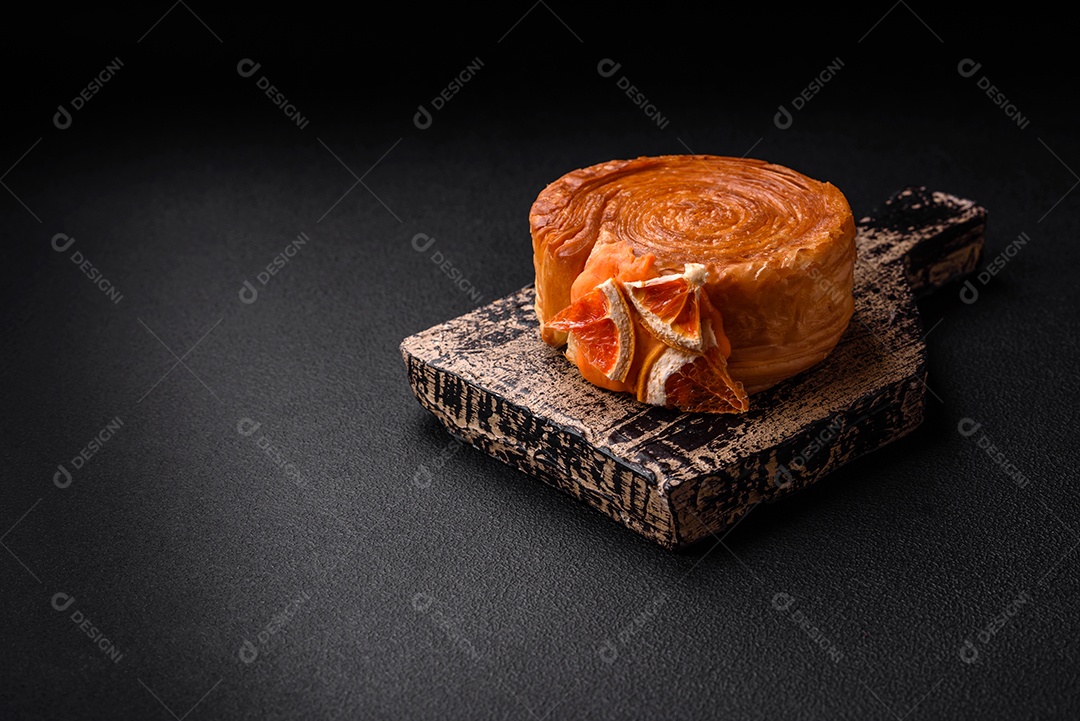 Croissant redondo de massa folhada com recheio de frutas cítricas ou rolo de Nova York sobre fundo escuro de concreto
