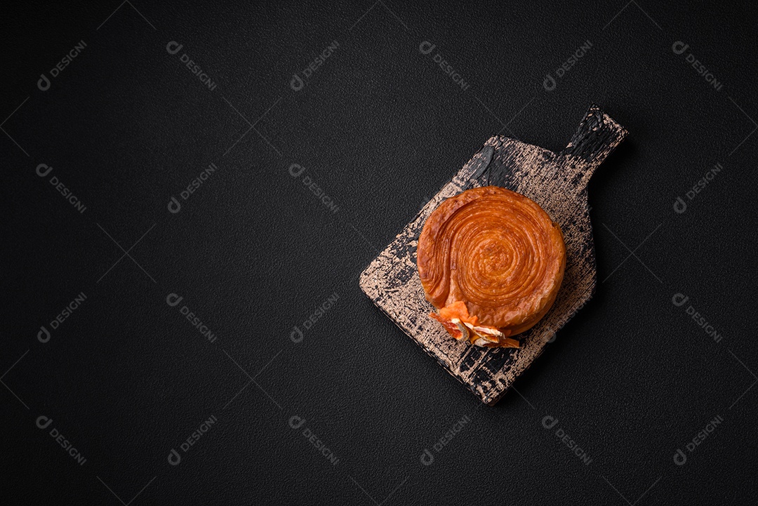 Croissant redondo de massa folhada com recheio de frutas cítricas ou rolo de Nova York sobre fundo escuro de concreto