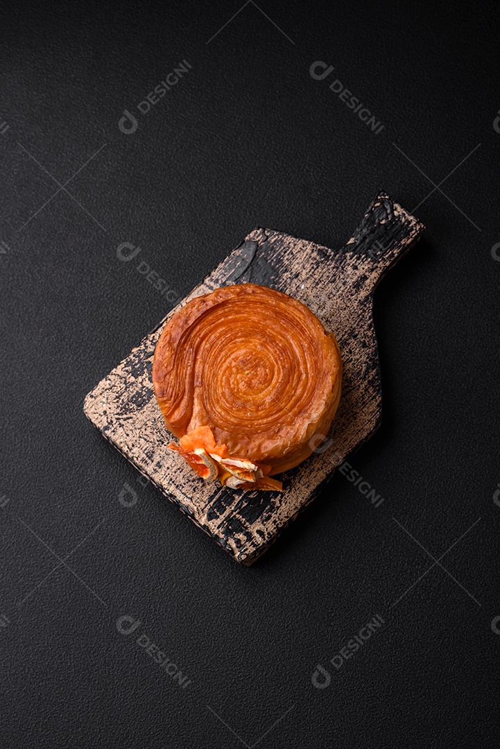 Croissant redondo de massa folhada com recheio de frutas cítricas ou rolo de Nova York sobre fundo escuro de concreto