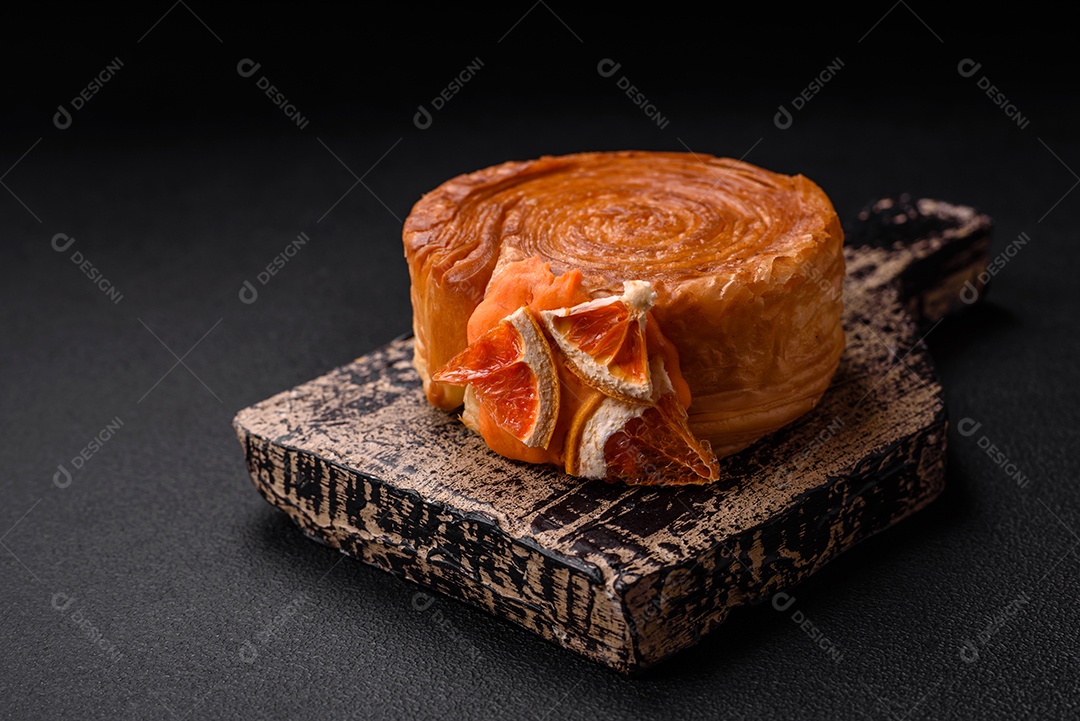 Croissant redondo de massa folhada com recheio de frutas cítricas ou rolo de Nova York sobre fundo escuro de concreto