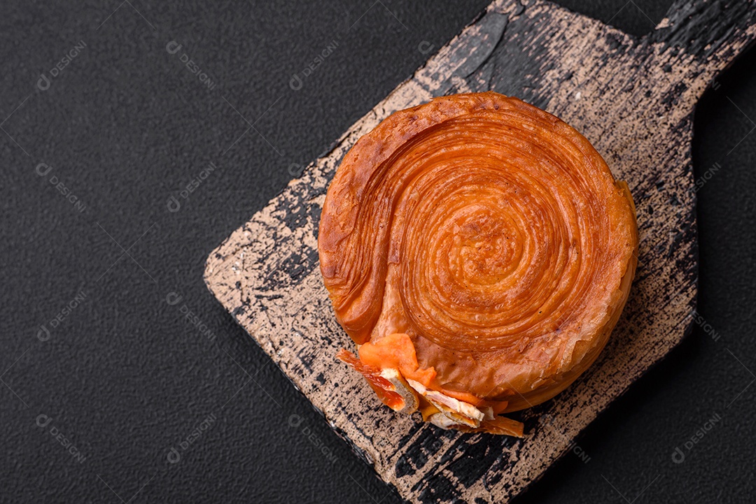 Croissant redondo de massa folhada com recheio de frutas cítricas ou rolo de Nova York sobre fundo escuro de concreto