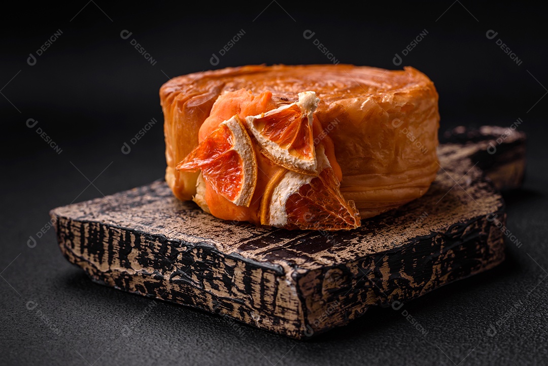 Croissant redondo de massa folhada com recheio de frutas cítricas ou rolo de Nova York sobre fundo escuro de concreto