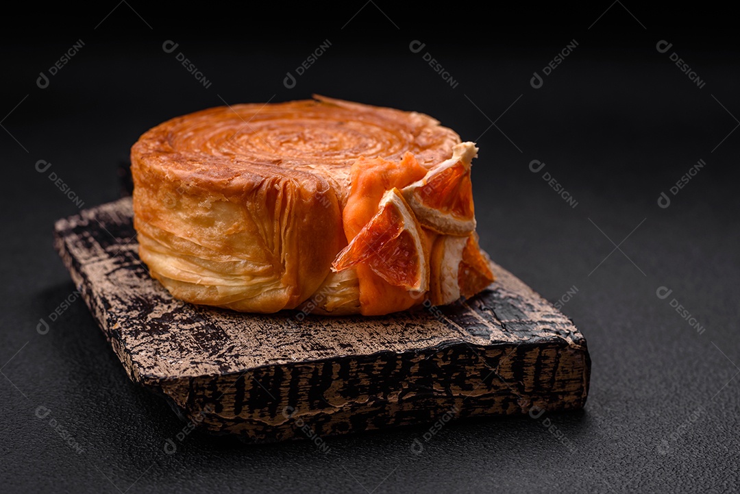 Croissant redondo de massa folhada com recheio de frutas cítricas ou rolo de Nova York sobre fundo escuro de concreto