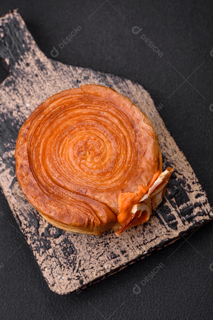 Croissant redondo de massa folhada com recheio de frutas cítricas ou rolo de Nova York sobre fundo escuro de concreto
