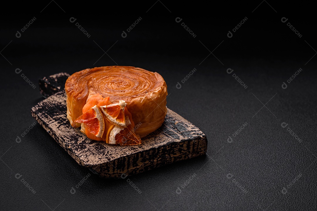 Croissant redondo de massa folhada com recheio de frutas cítricas ou rolo de Nova York sobre fundo escuro de concreto