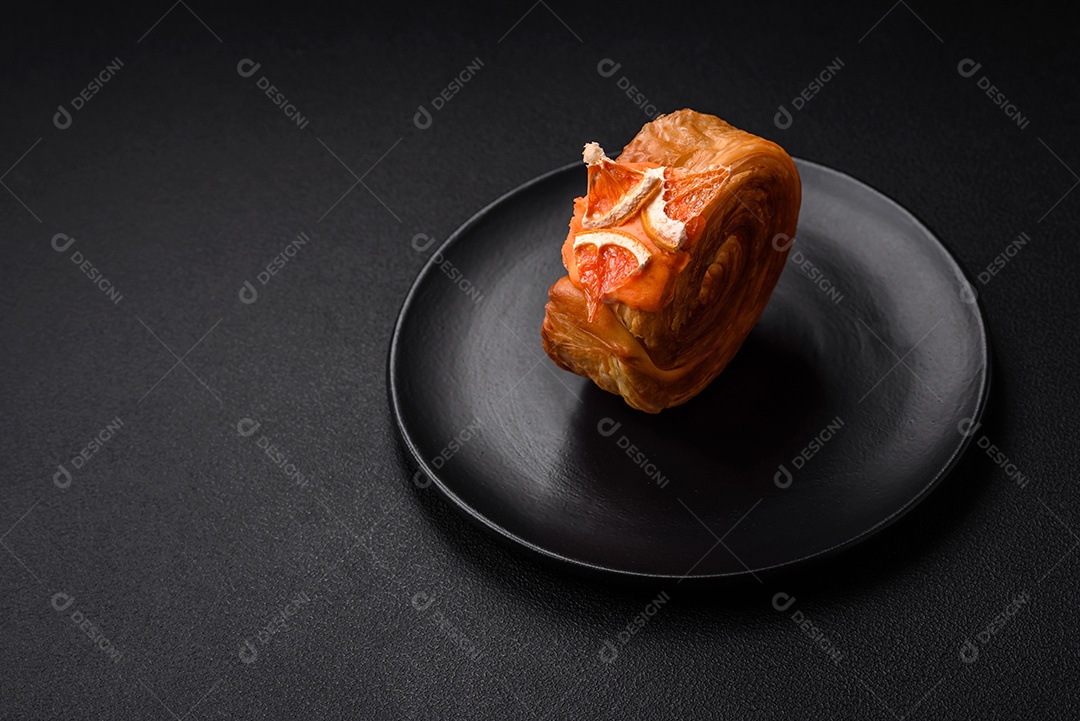Croissant redondo de massa folhada com recheio de frutas cítricas ou rolo de Nova York sobre fundo escuro de concreto