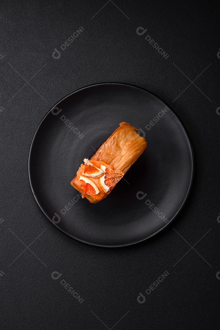 Croissant redondo de massa folhada com recheio de frutas cítricas ou rolo de Nova York sobre fundo escuro de concreto